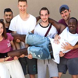 Fünf junge Menschen halten einen sechsten Mann auf Armen noch